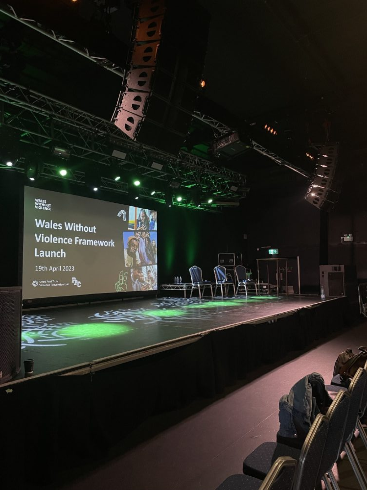 This image shows the stage with the slides ready for presentations. It includes the speakers chairs and green stage lights.