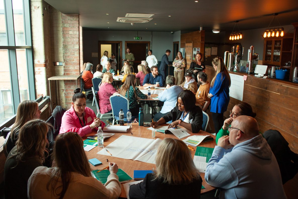 This image shows people attending the event in a workshop, in conversation and writing ideas down.